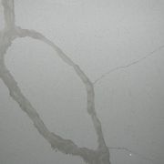 Detailed close-up of ST Quartz Calacatta Glacier, showcasing the broad, soft-edged grey veins and subtle hairline cracks on a finely speckled white base