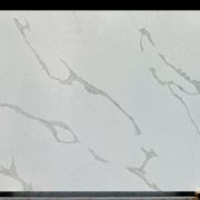 Full slab of ST Quartz Calacatta Glacier, a marble-effect quartz with bold, flowing veins of warm grey on a cool white, glacier-like background