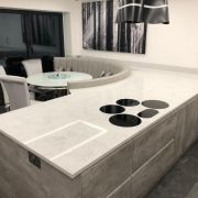 Bespoke kitchen worktop in ST Quartz Carrara Dove, expertly curved to form an integrated banquette seating area next to a flush-mounted hob