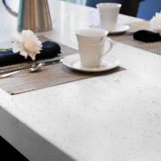 An elegant dining setting on a clean, white Nile Quartz Carrara Spring worktop, perfect for modern living and entertaining