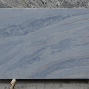 Full slab of ST Quartz Cielo, a unique quartz featuring waves of soft, tonal blue veins on a dusty slate-blue background, evoking a cloudy sky