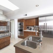 A professional-style kitchen design pairing warm Silestone Coral Clay worktops with wood cabinetry and stainless steel appliances