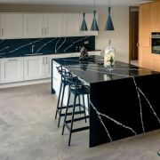 A striking two-tone kitchen design showcasing a seamless waterfall island in black and white Silestone Eternal Marquina quartz