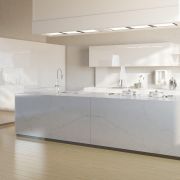 An all-white, contemporary kitchen design showcasing the bold, cloudy veining of Nile Quartz Calacatta Alaska on a seamless waterfall island