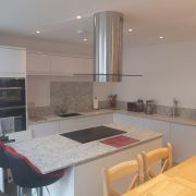 Modern kitchen installation featuring ST Quartz Snowdon on the worktops, island breakfast bar, and matching full-height splashback
