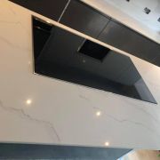 Luxury kitchen island featuring an ST Quartz Statuario Premium worktop with a seamlessly integrated extractor hob.