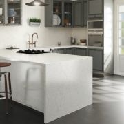 Beautiful two-tone kitchen design showcasing a seamless waterfall island in finely-veined Silestone Pearl Jasmine quartz