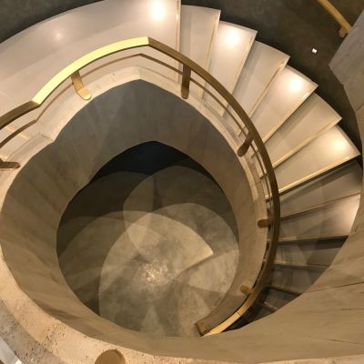 Quartz spiral staircase with Brass inlaid strips manufactured and installed by ST Stone Works.